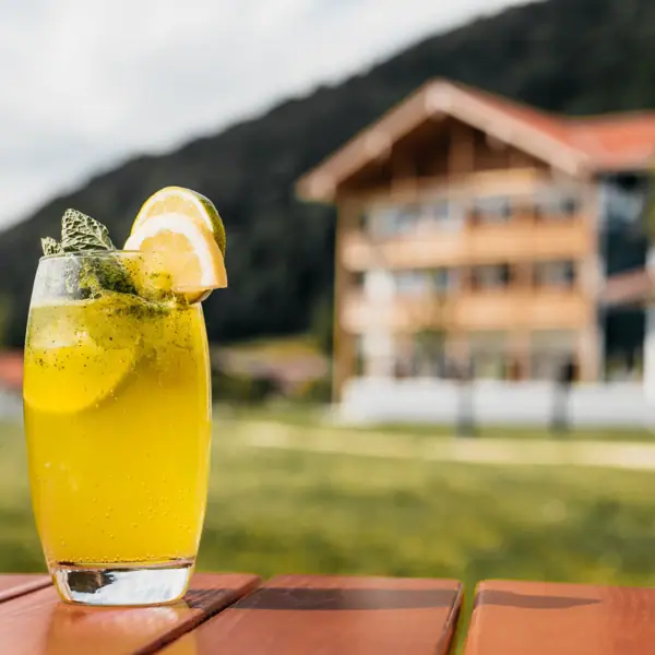 Drink at aja Ruhpolding Lemonade in a glass and with the aja Ruhpolding in the background.