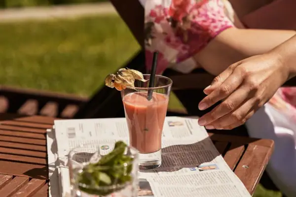 Smoothie A person is sitting at a table with a drink on a newspaper.