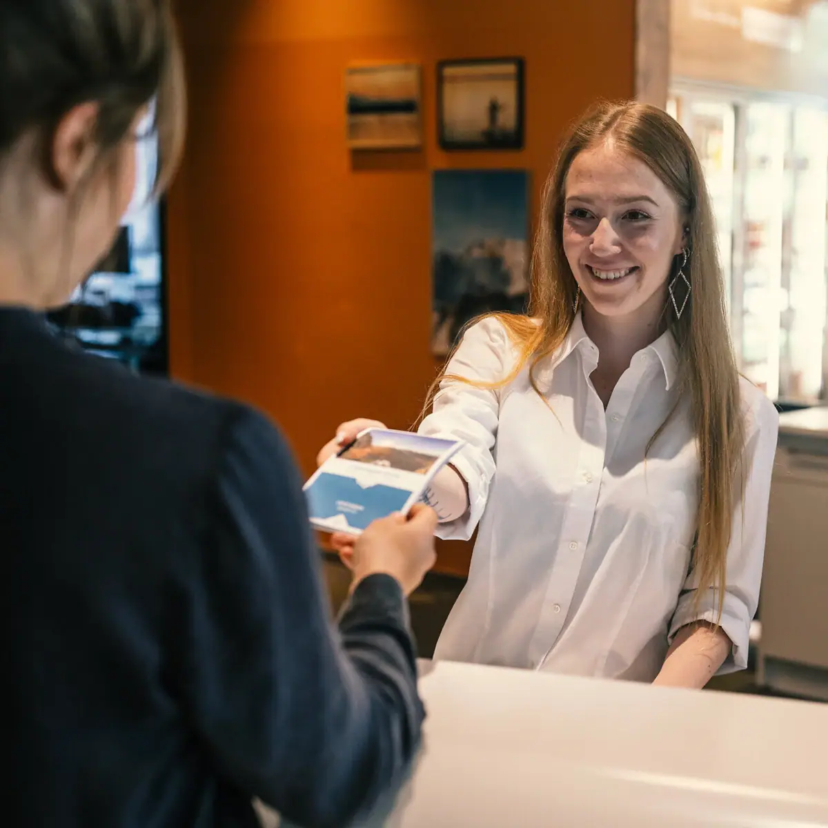 A woman hands a card to a customer.