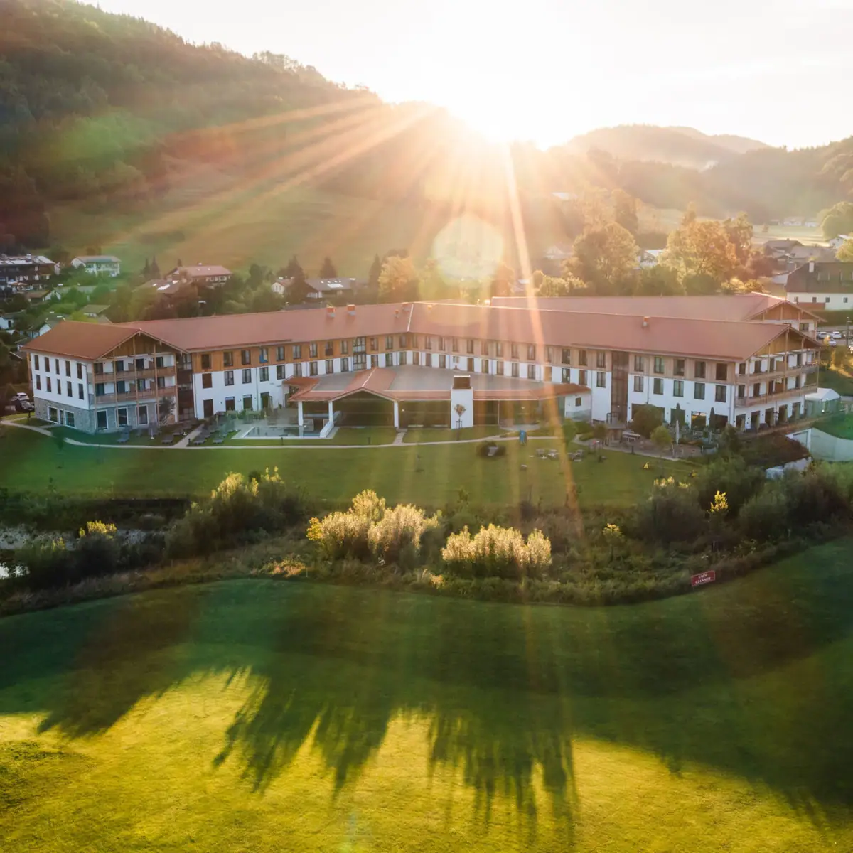 A large building with a large lawn and a car park.
