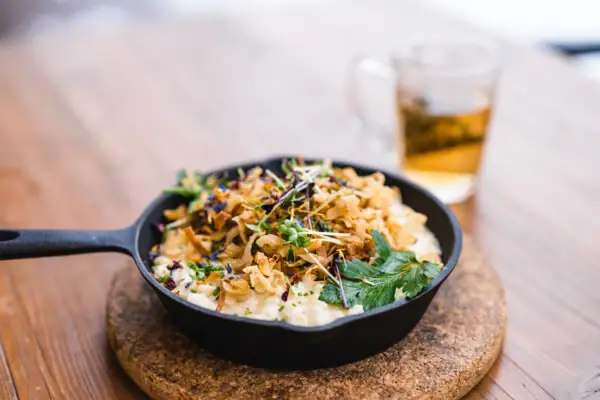 Cheese spaetzle A pan with food on a table.