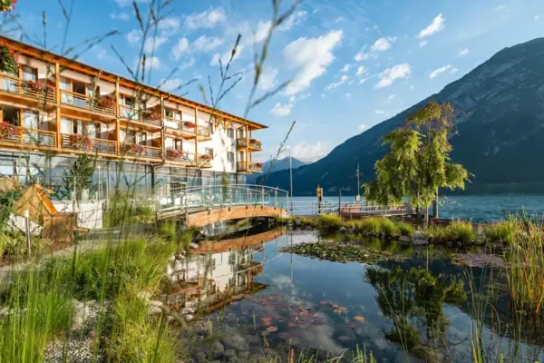 A building next to a body of water with trees and clouds in the sky.