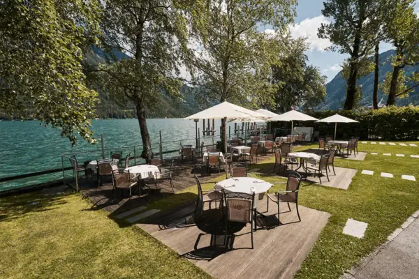 A table and chairs on a deck by the lake.
