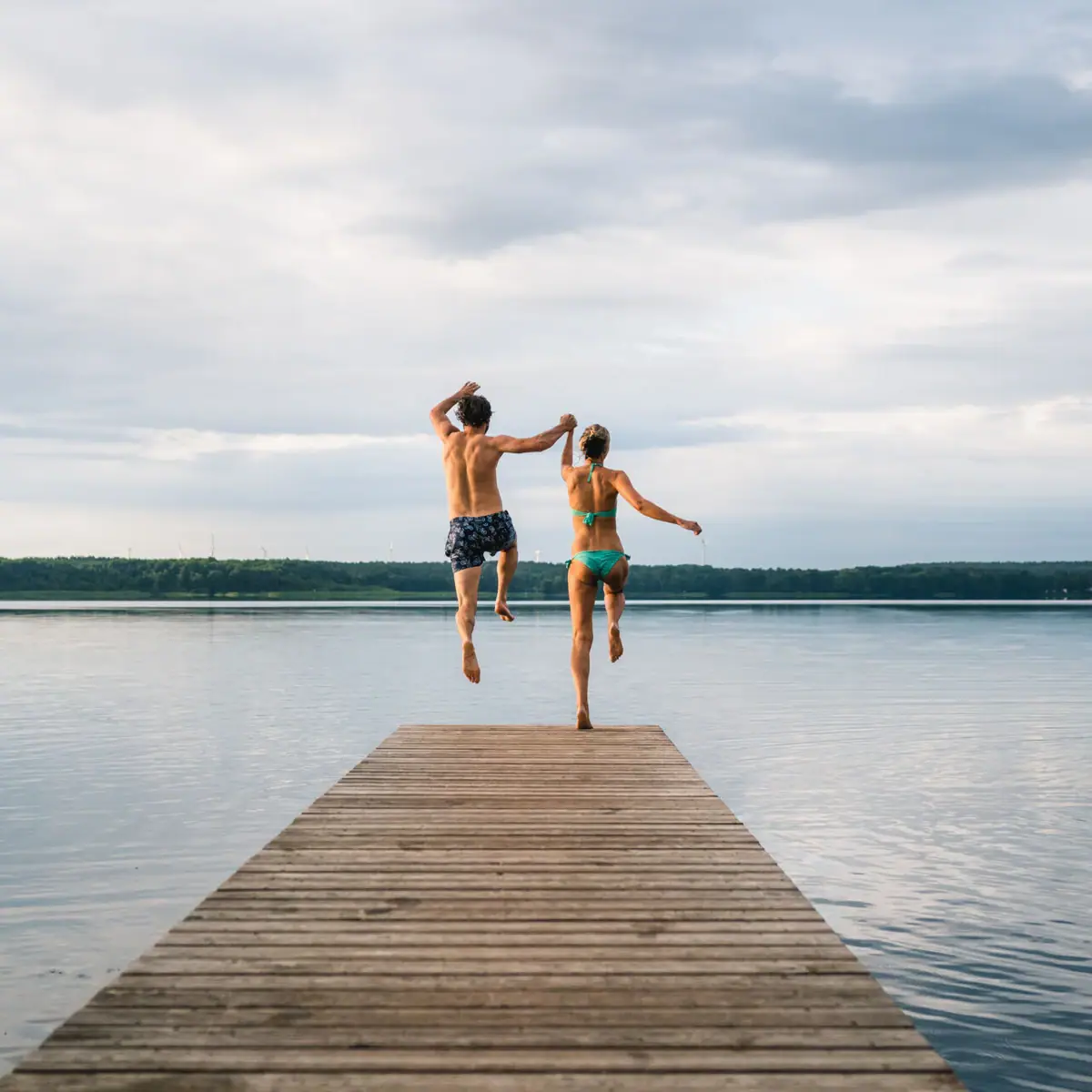 Jump into the lake A man and a woman jump into the water.
