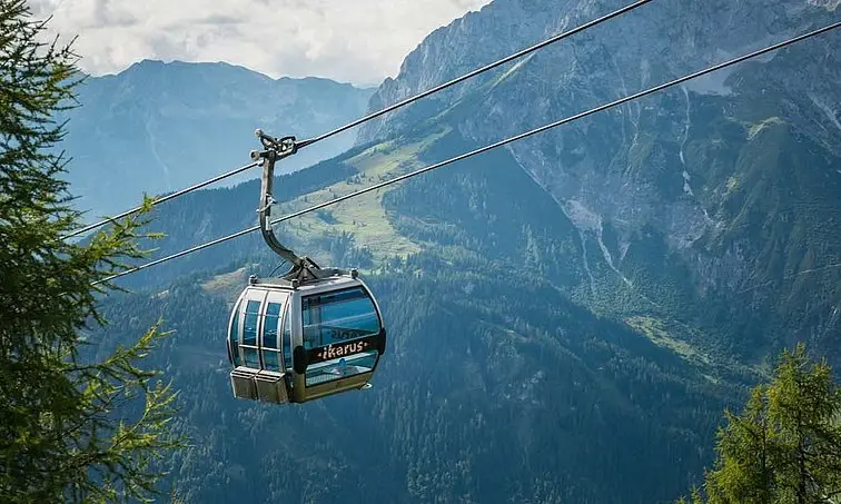 Cable car in front of a mountain panorama.