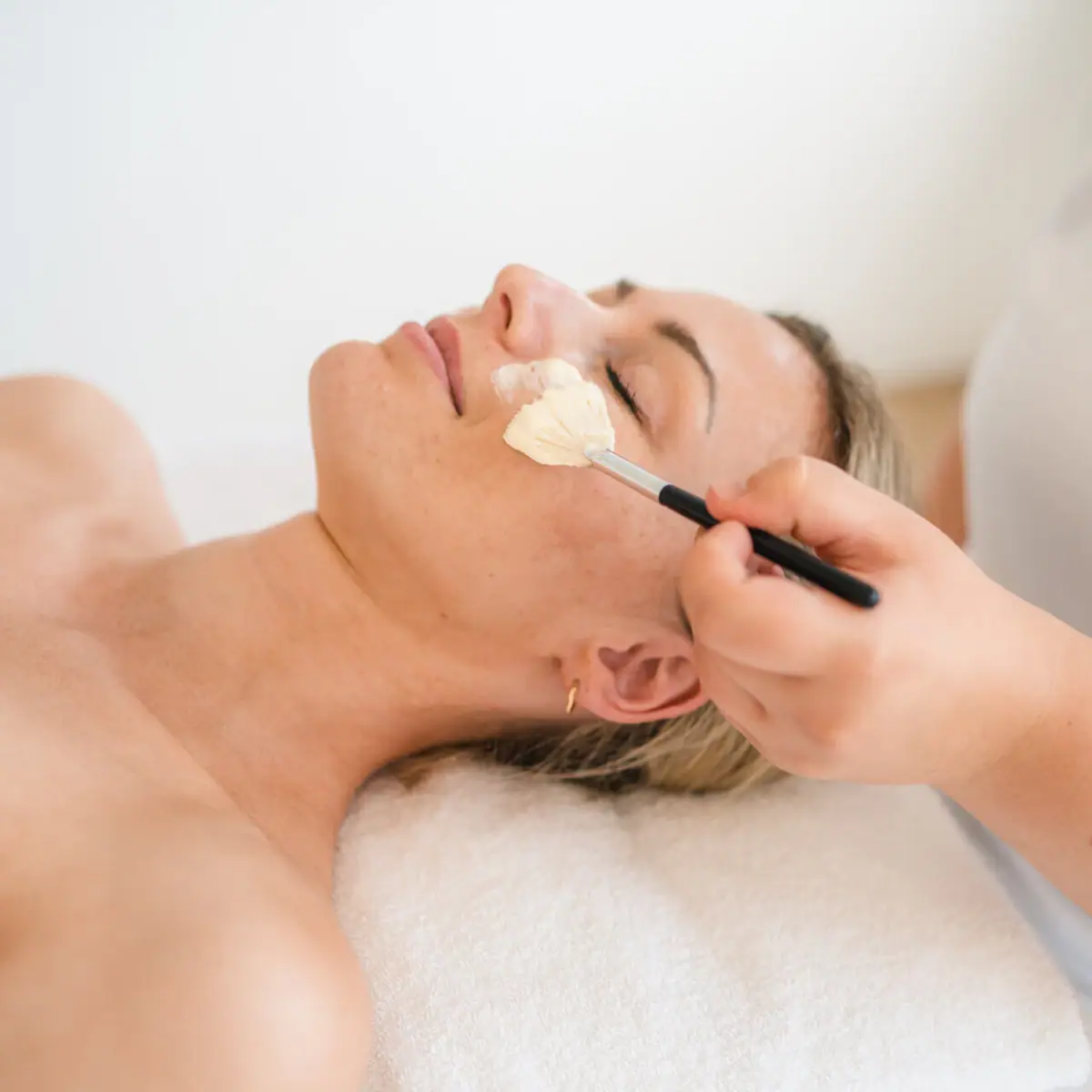 Facial application Woman lying with a brush on her face.