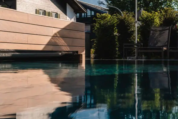 A swimming pool with chairs and parasols set against a mountain backdrop.
