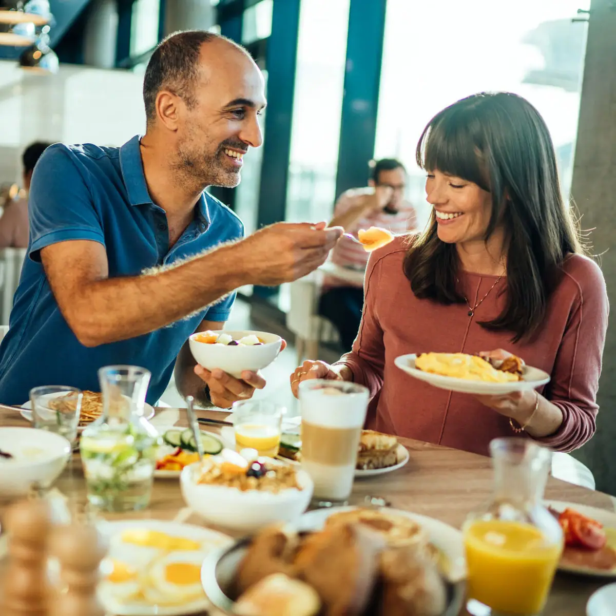 A man and a woman are eating at a table.