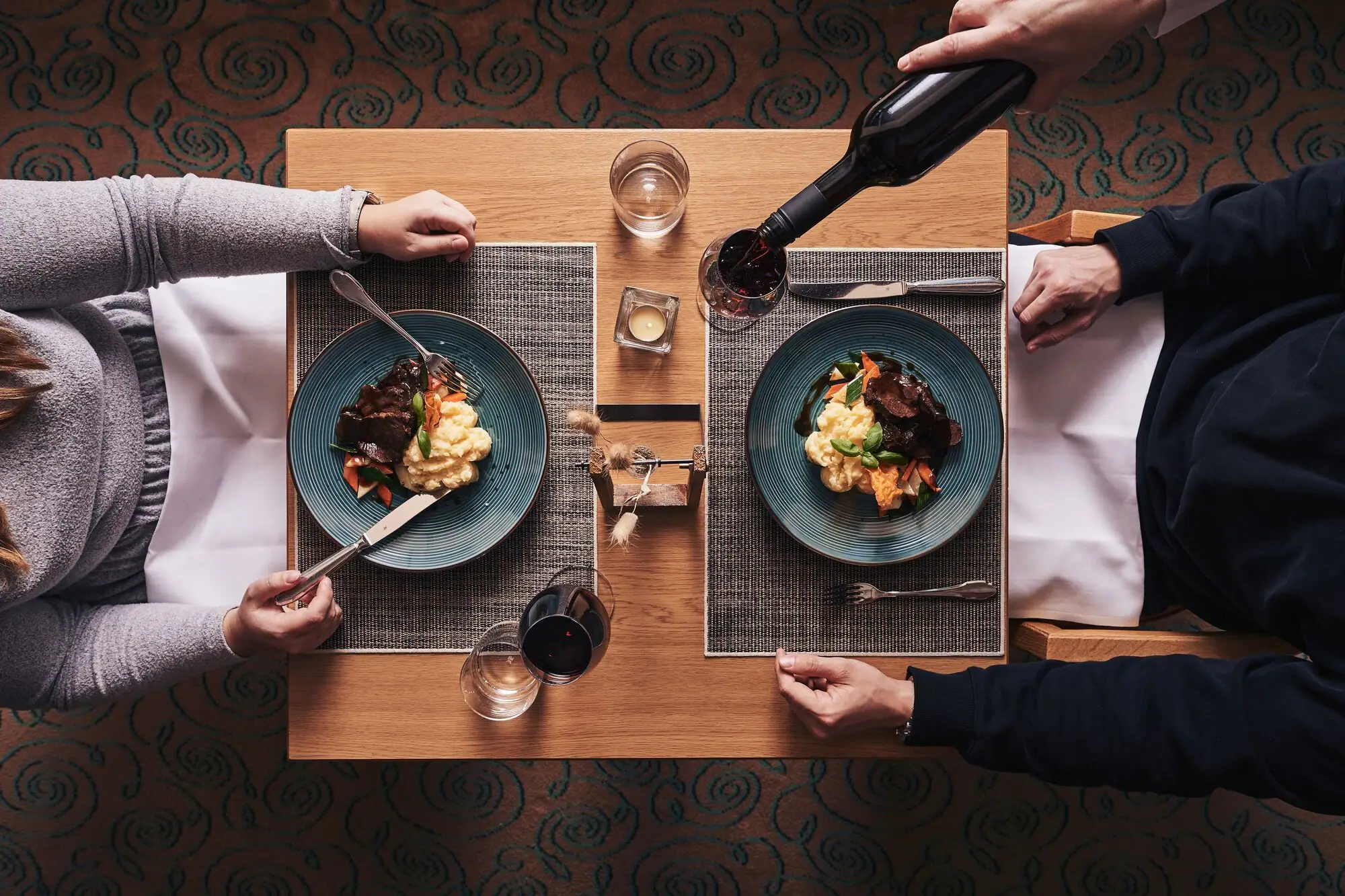 Restaurant Flora A person holds a bottle of wine and eats food.