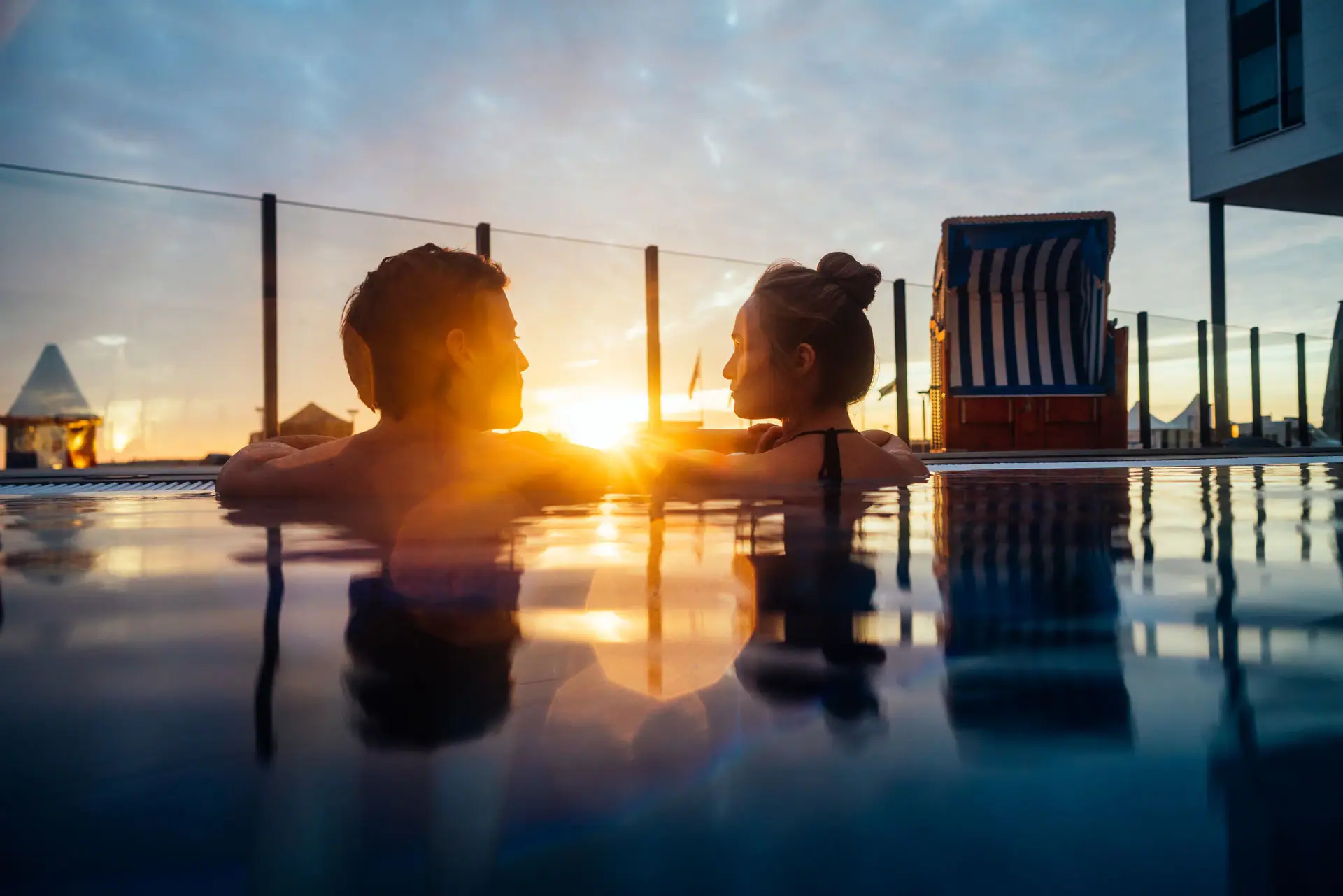 A man and a woman in the outdoor pool at sunset.