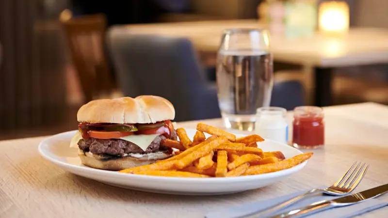 Buger A plate of chips and a sandwich on a table.