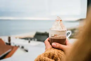 Eine Person hält eine Tasse heiße Schokolade mit Sahne.