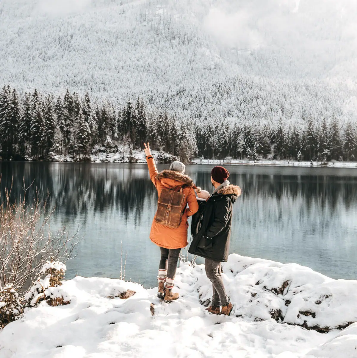 Winter landscape Two people are standing on the snowy shore of a lake.