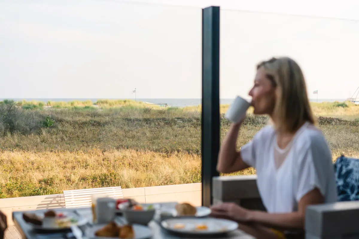 A woman is sitting at a table with a cup of coffee.