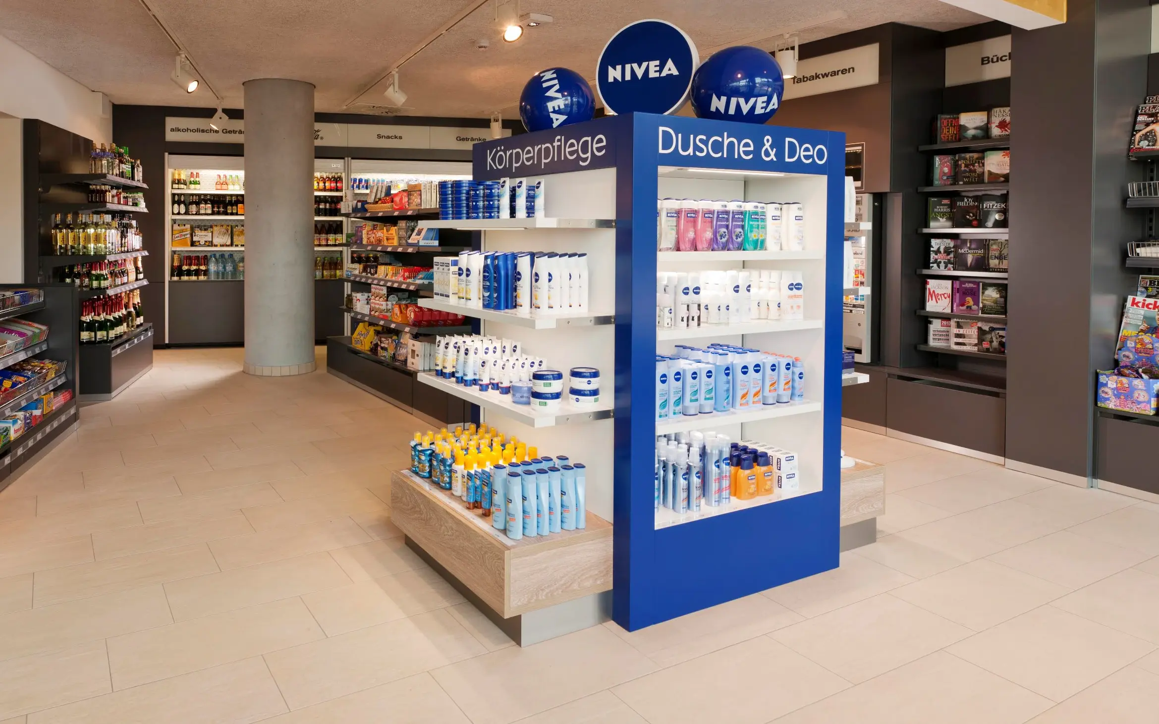 Hotel shop with a NIVEA display, snacks, drinks, and magazines in a modern, inviting atmosphere.