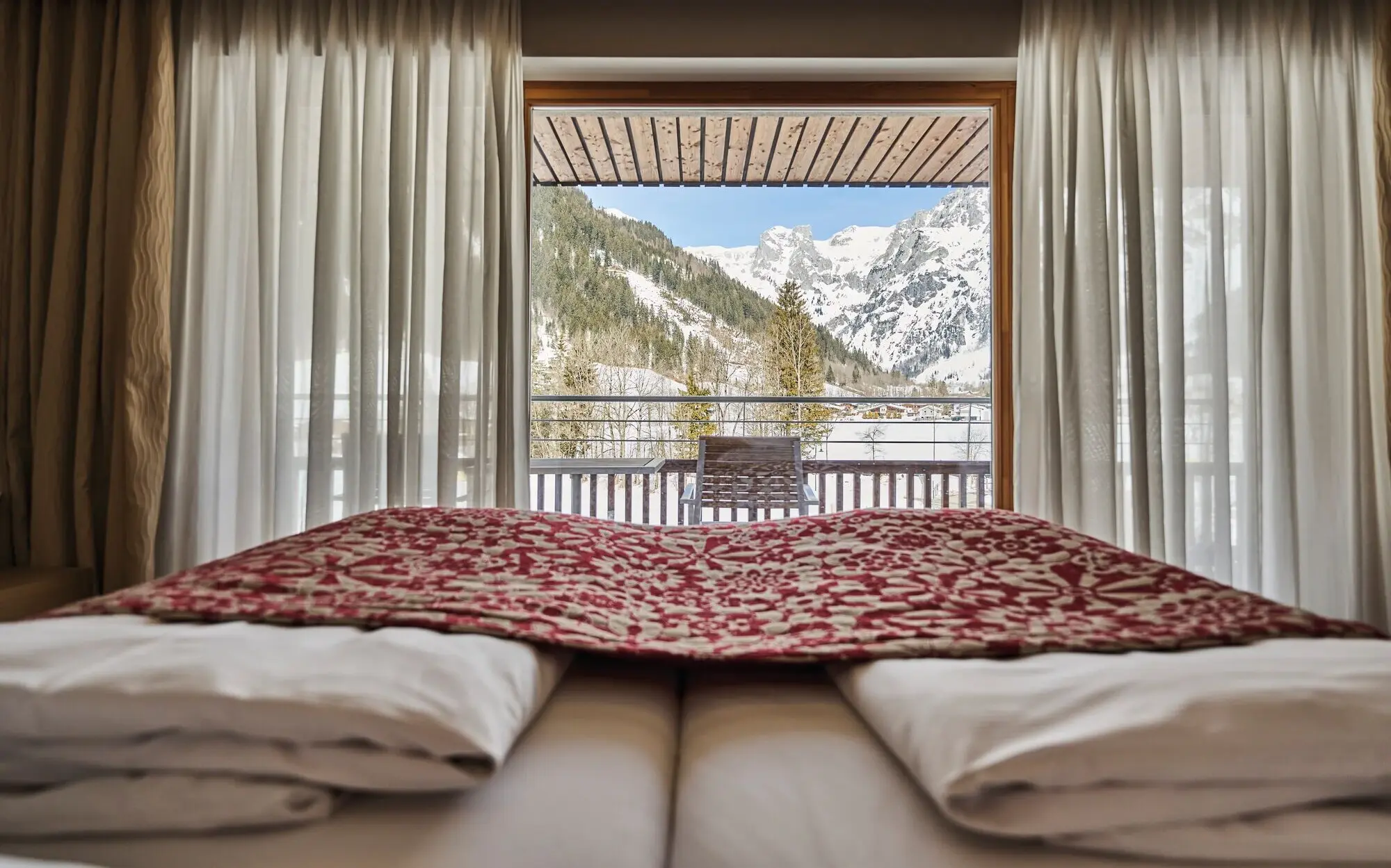 A bed with a view of the mountains, surrounded by cozy bed linen and pillows.