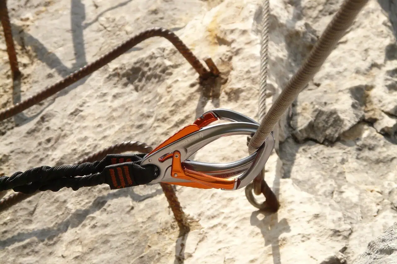 Close-up of a carabiner attached to a wire rope in a rock.