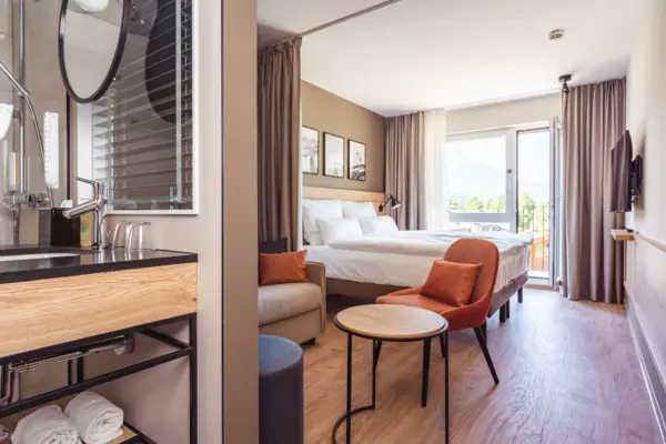 Ein modernes, helles Hotelzimmer mit einem Bett und einem Tisch.