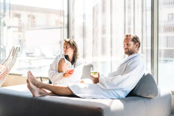 SPA Lounge A man and a woman in bathrobes are sitting on a sofa.
