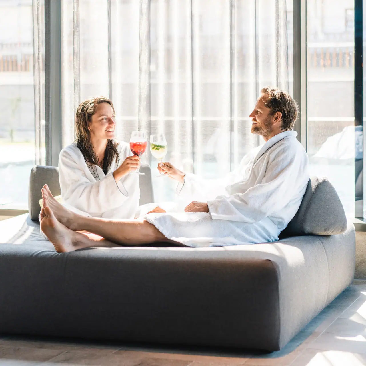 Couple does wellness A man and a woman in bathrobes are sitting on a sofa.