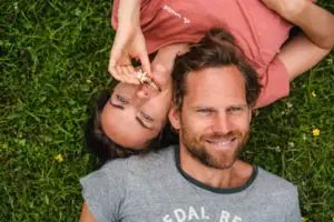 A man and a woman lie smiling on grass.