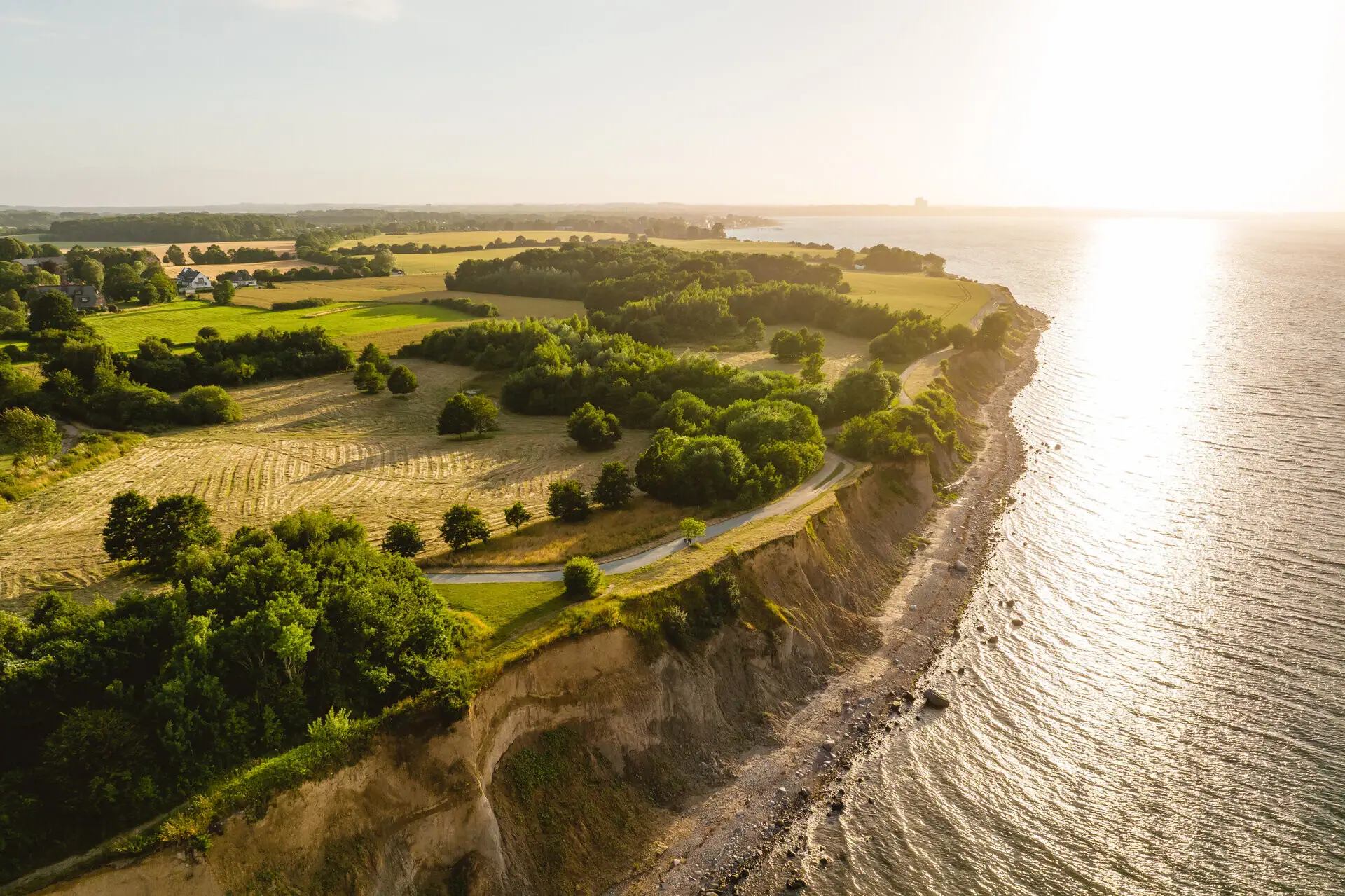 Aerial view of a beach with a grassy area and trees and a steep bank.