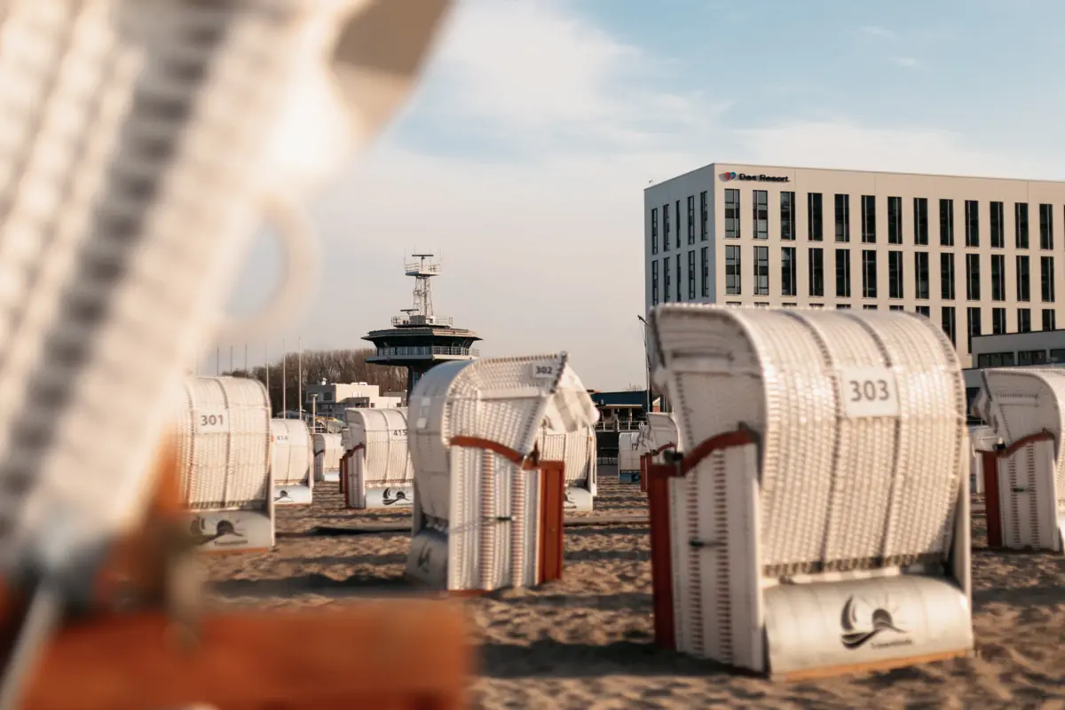 Group of white beach chairs on the beach under a blue sky with veil clouds.