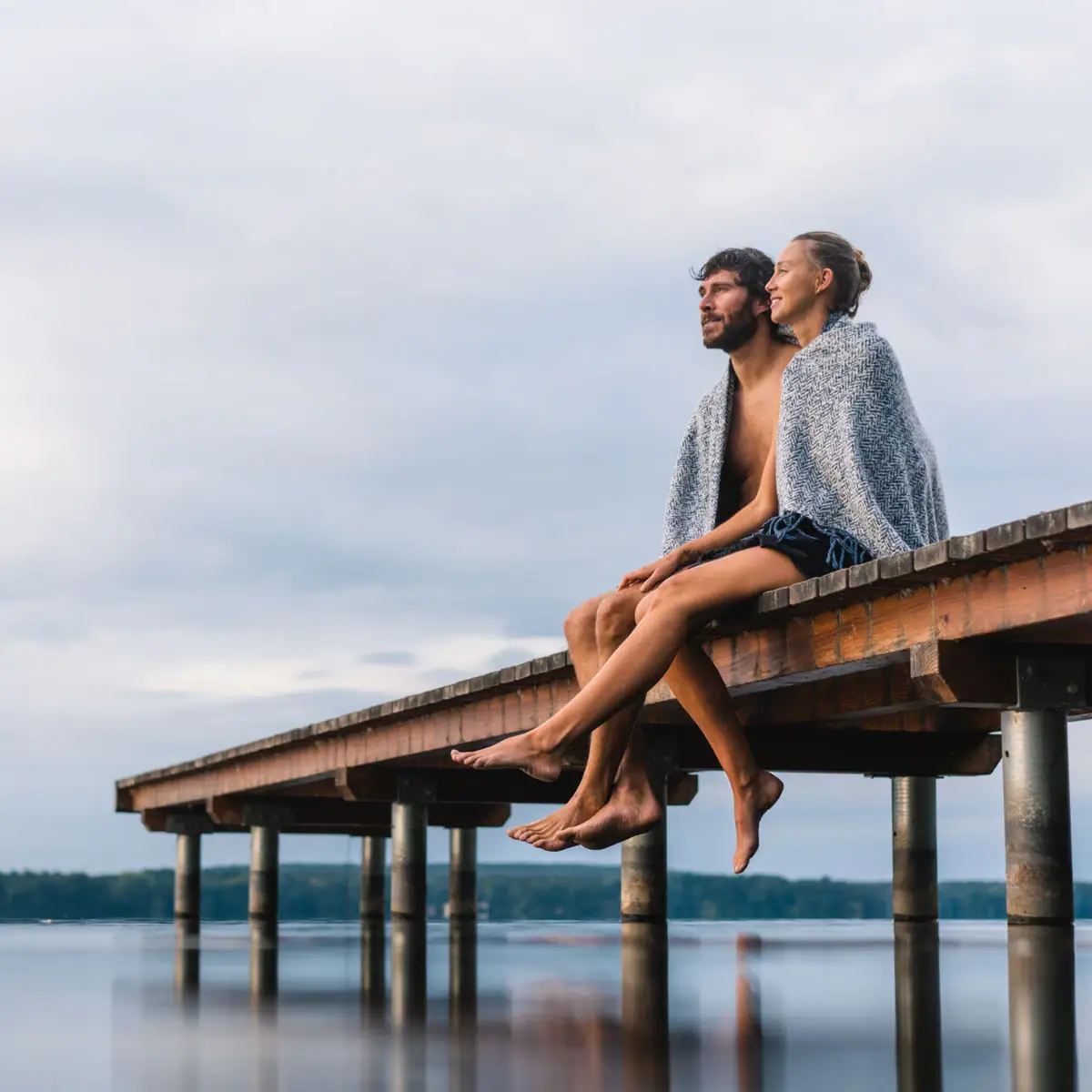 A man and a woman are sitting on a footbridge.