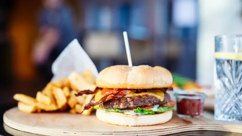 Burger and fries on a wooden board.