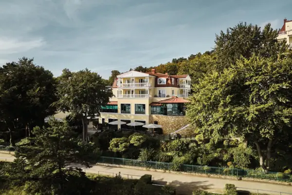 Exterior view of the aja Bansin surrounded by green trees on a sunny day. 