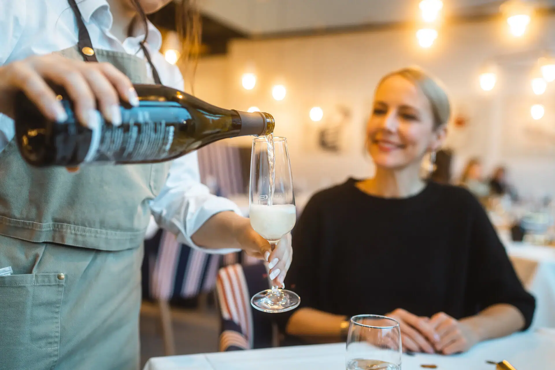 A woman pours wine into a glass.