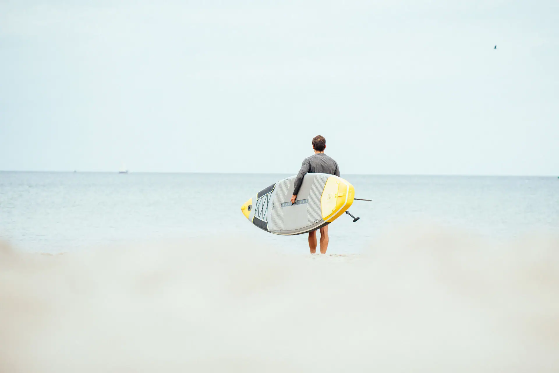 A man holds a surfboard on the beach.