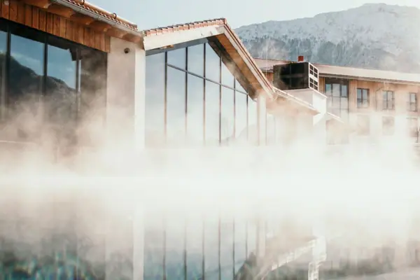 A building in front of a body of water, with a mountain in the background.