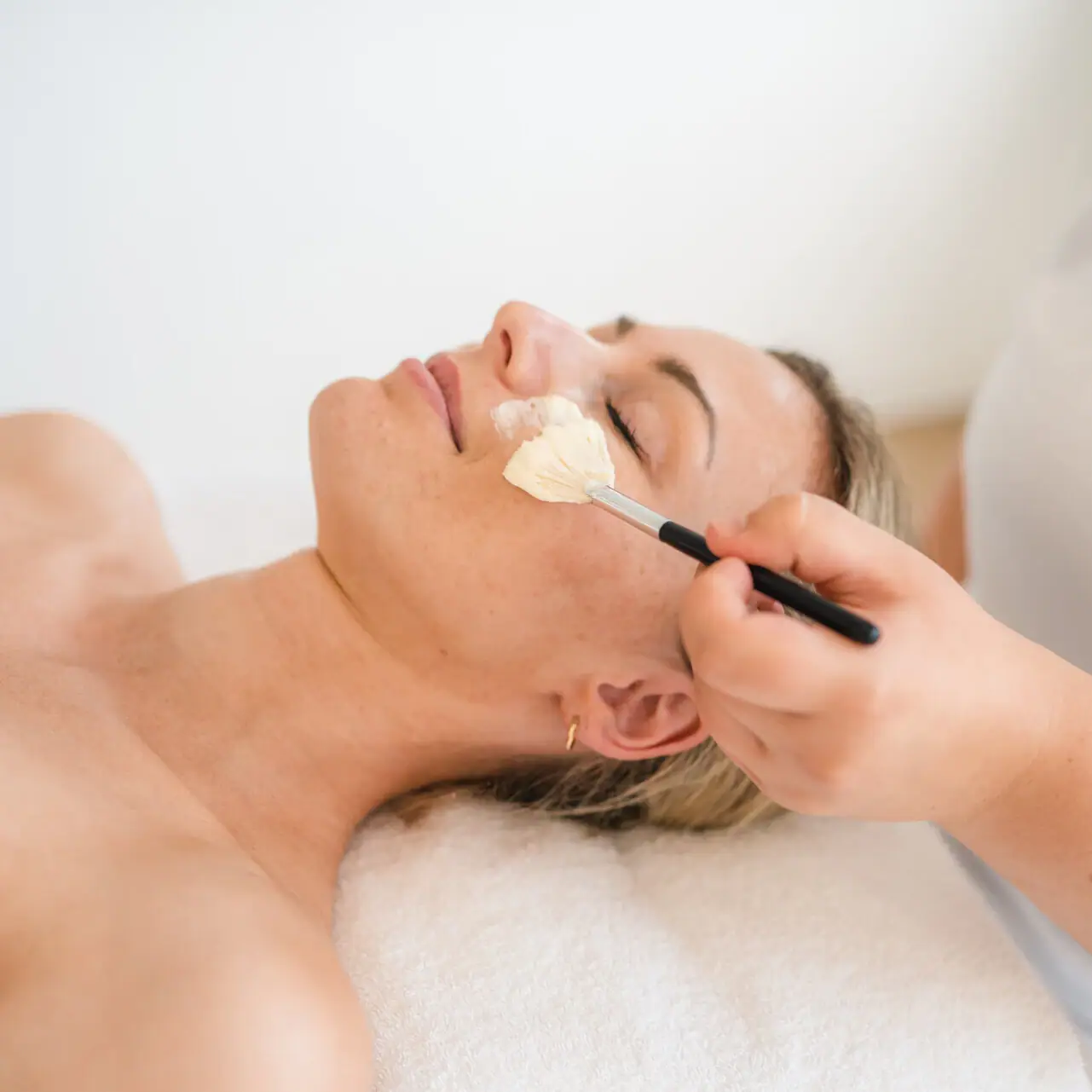 Applications at the aja Warnemünde A woman lies on the couch with a brush on her face.
