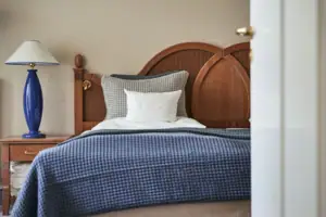 A bed with a blue blanket and a white pillow.