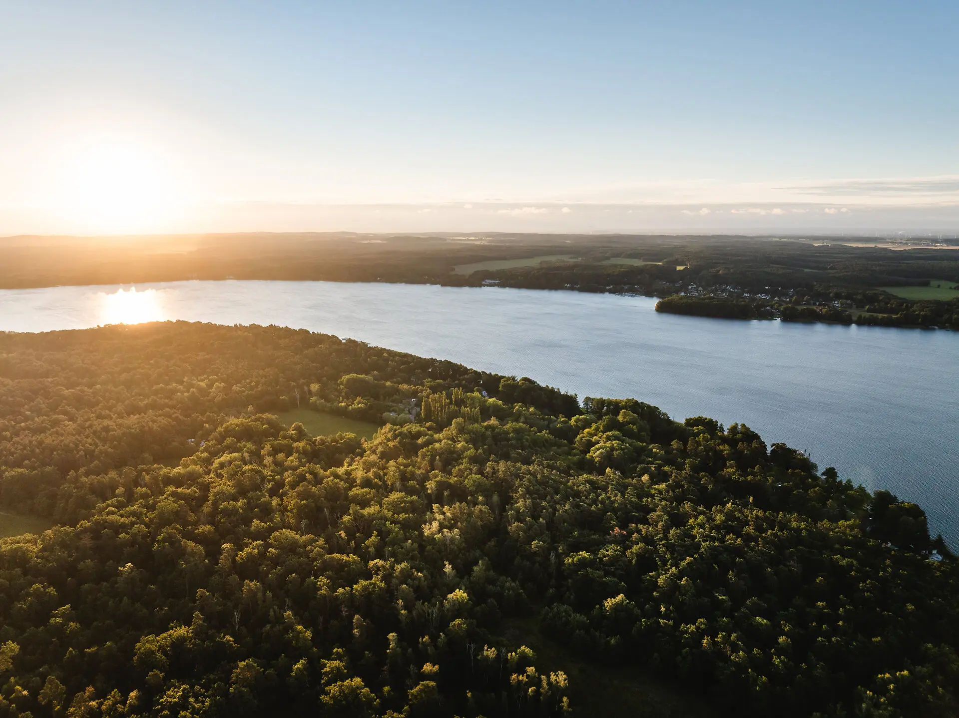 A big lake and surrounding green nature during sunrise. 