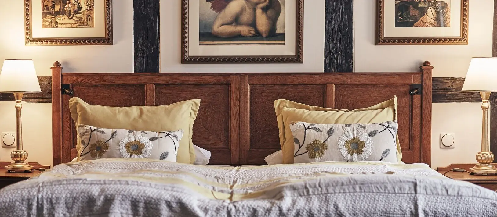 A bed with a wooden headboard and two framed pictures above it.