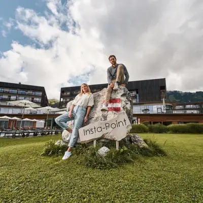 A man and a woman are sitting on a rock with a sign outside.
