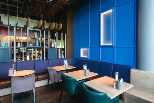 Bar Blaue Sitzbank mit Tischen und Stühlen in einem Innenraum.