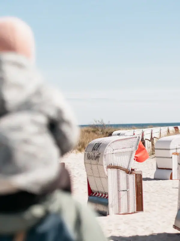 A person with a baby on their back on the beach.