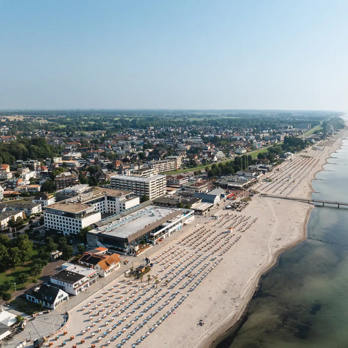 A bird's eye view of a beach with buildings and a body of water.
