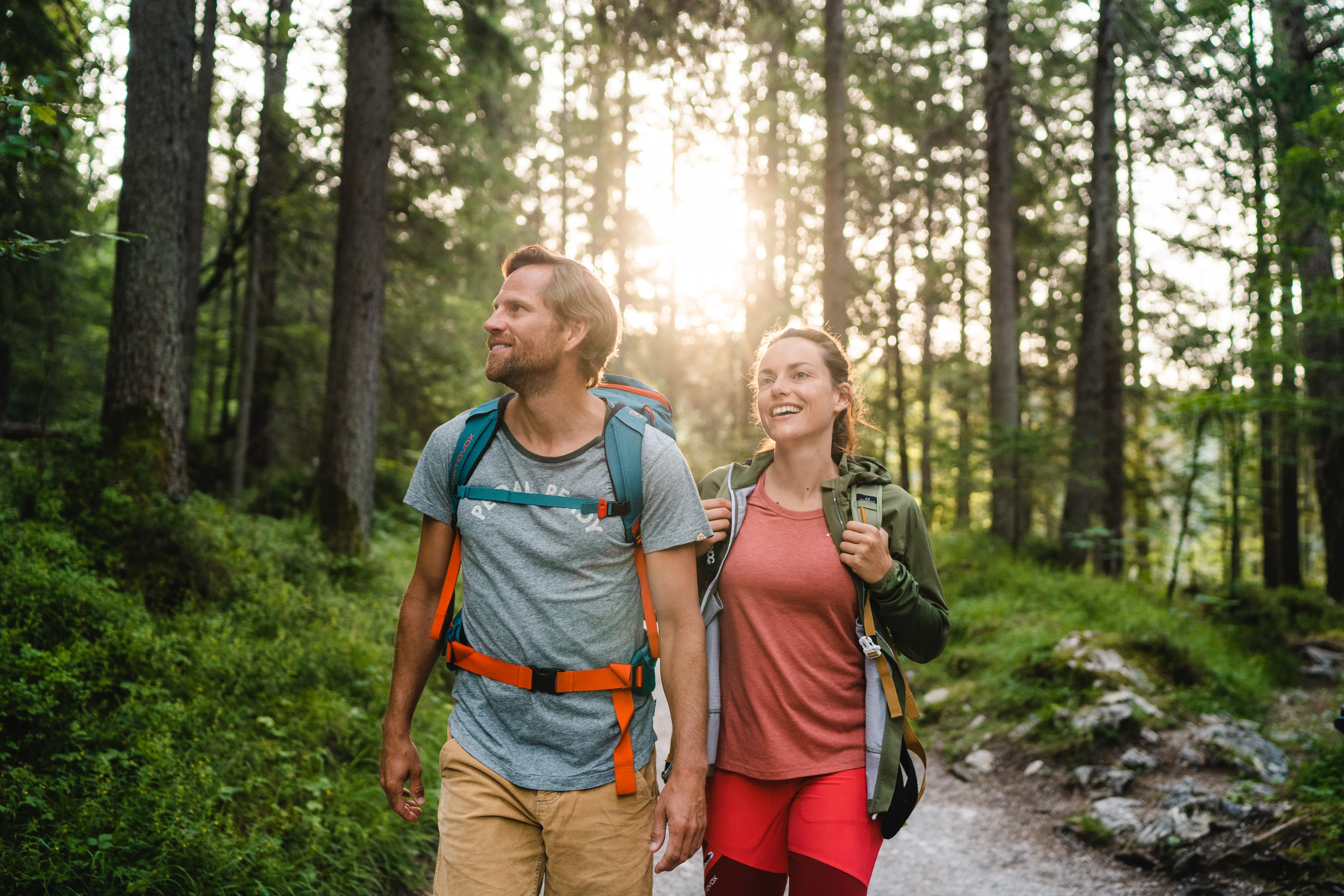 A man and a woman are walking through a forest.