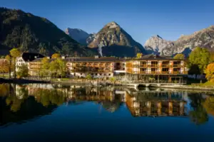 aja Fürstenhaus am Achensee A building next to a body of water with trees in the background.
