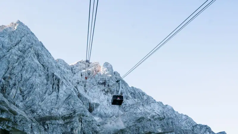 Cable car travelling up a mountain against a clear sky.