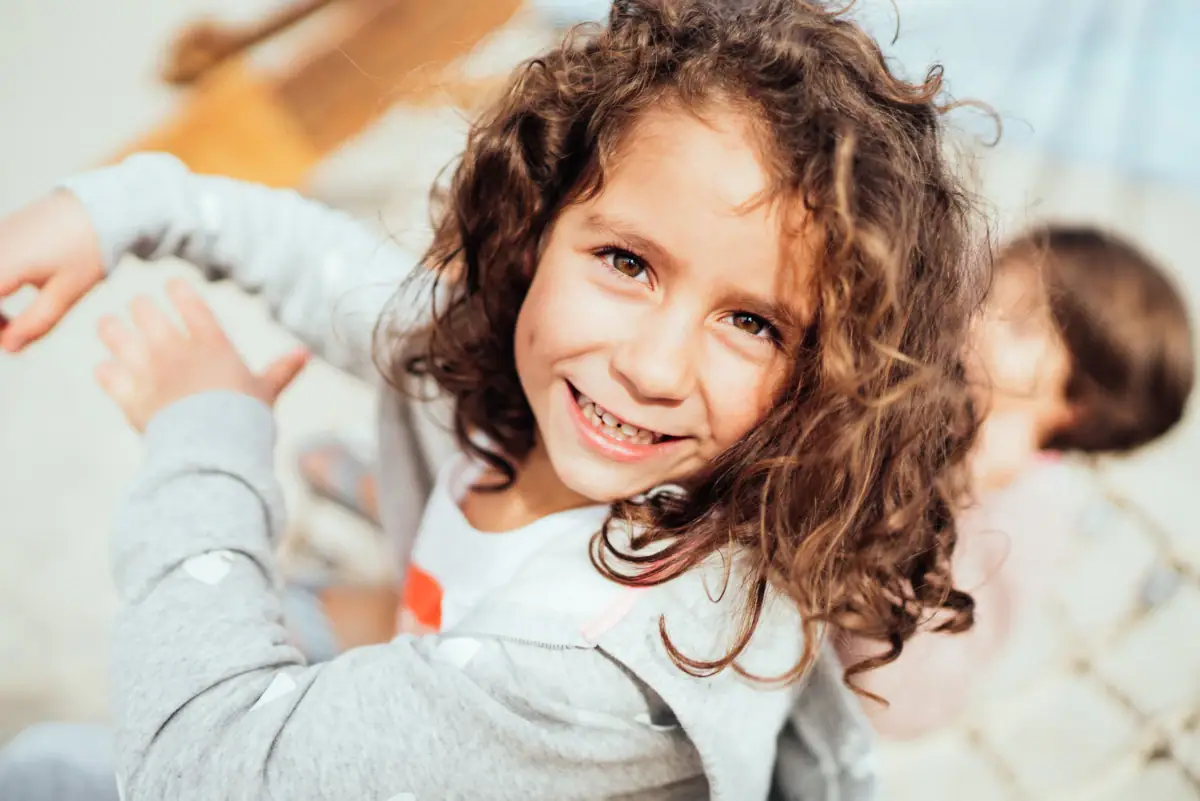 A girl with curly hair smiles.