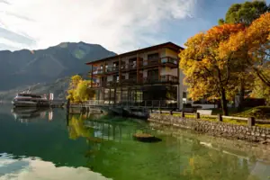 Ein Gebäude neben einem Gewässer mit Bäumen und Wolken im Hintergrund.