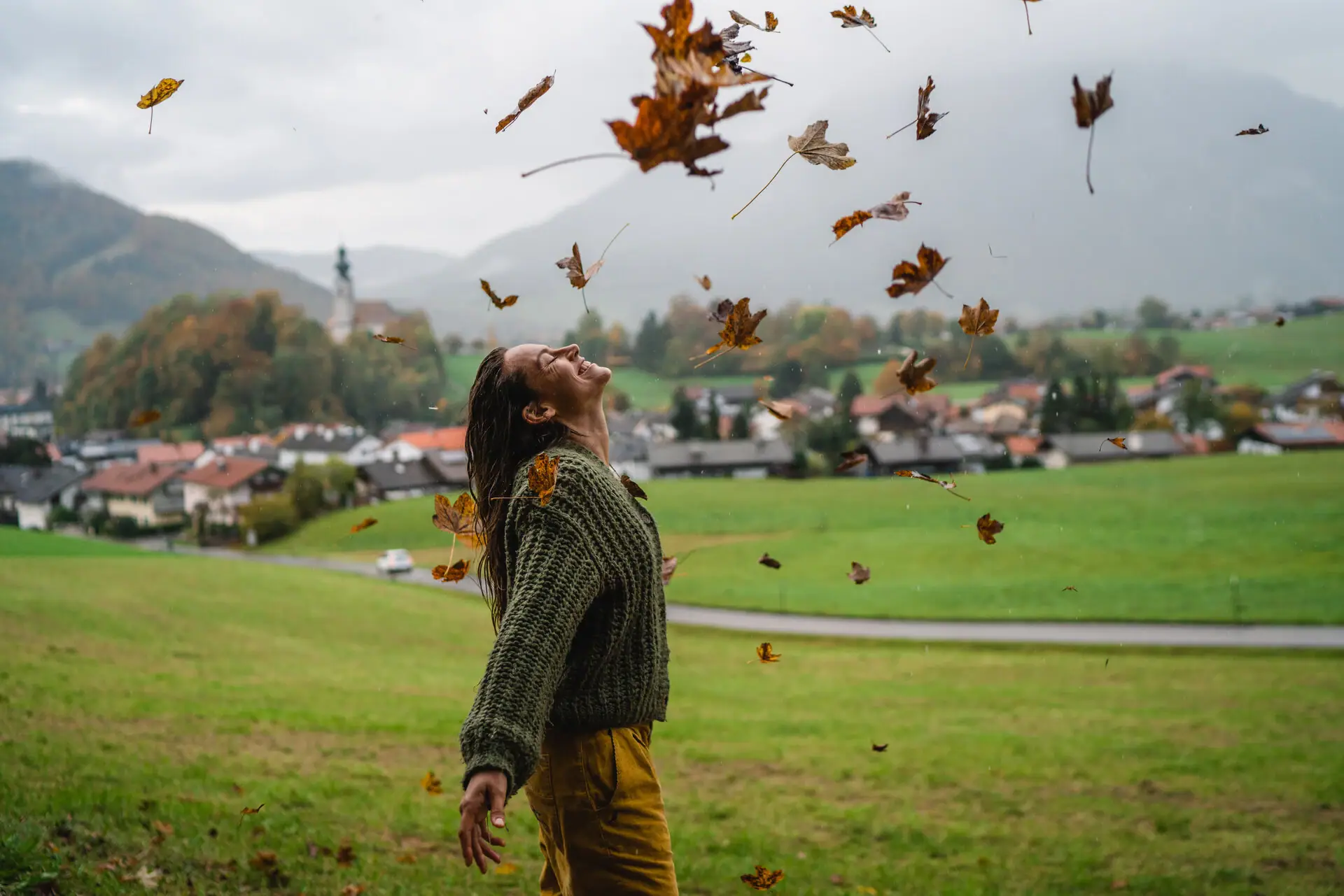 A woman throws leaves into the air.