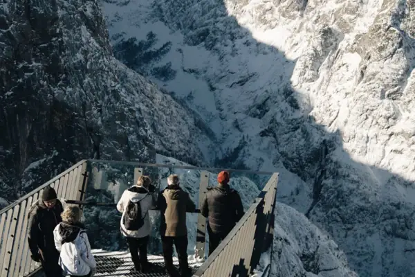 A group of people on a bridge over a snowy mountain.