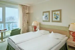 Double room facing the lake A bed with white sheets and a lamp in a room with a window.