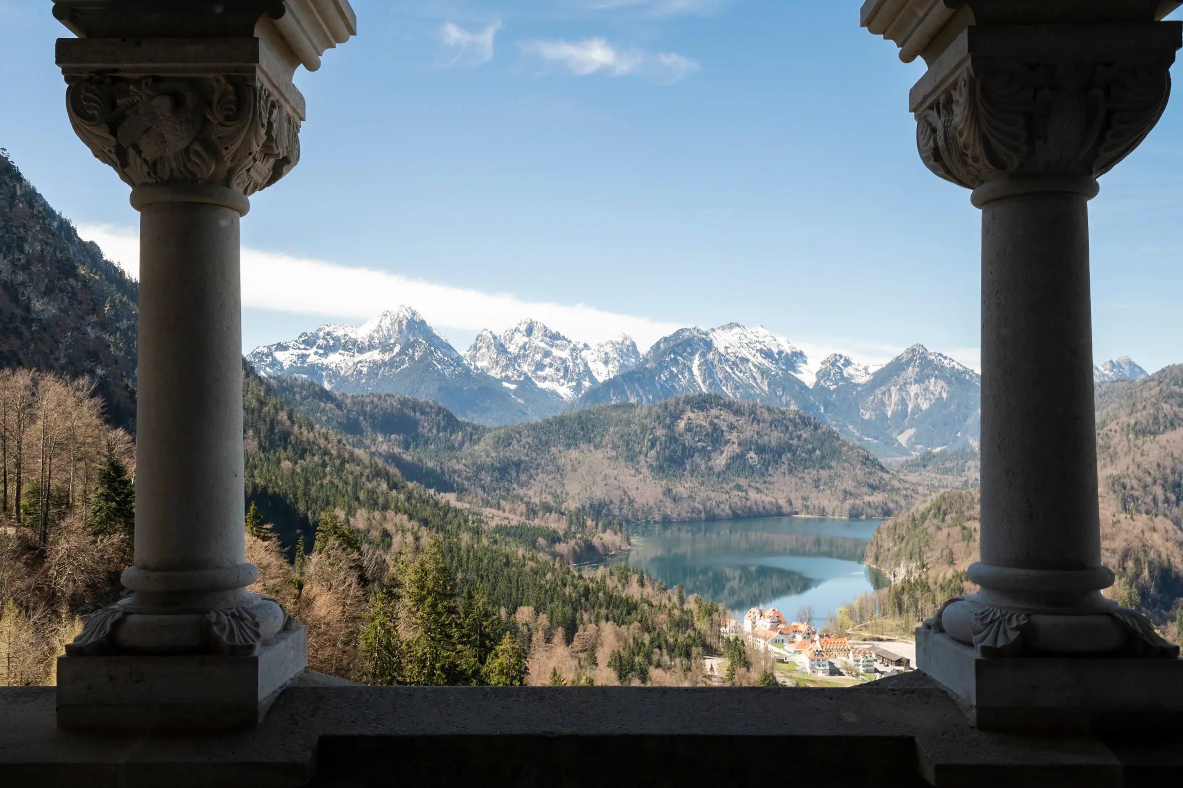 View of Neuschwanstein Castle View of a lake and mountains through two pillars.